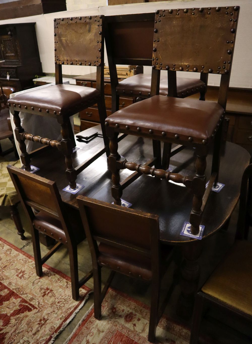A 1930s oak extending dining table 234cm extended (two spare leaves) and seven dining chairs (one with arms)